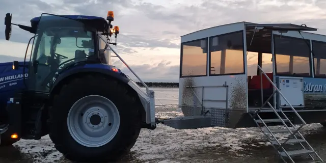 Un tracteur bleu et un bateau blanc sur une plage au coucher du soleil : La Balade d'Anton
