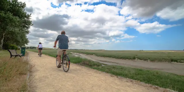 Two people cycling on a dirt path in the countryside