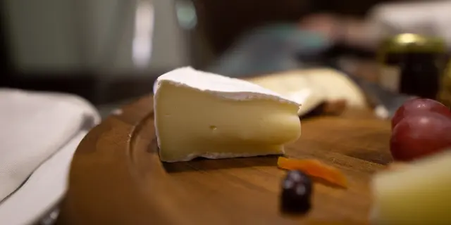 Assiette en bois avec du fromage, des raisins et des carottes
