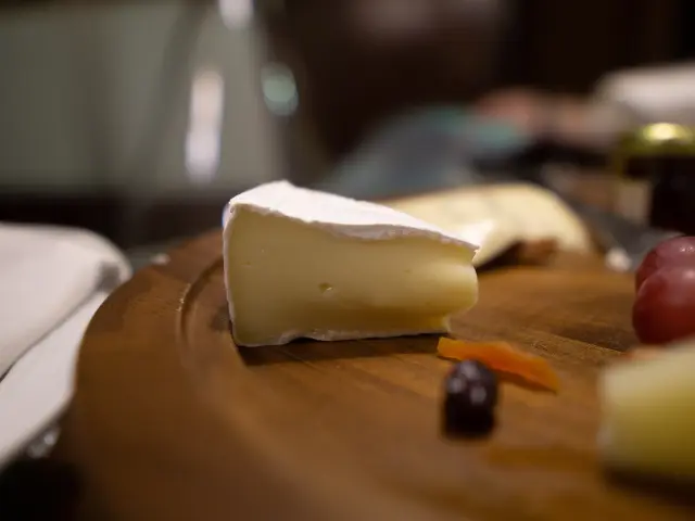 Une tranche de brioche dorée posée sur une table en bois avec des pommes rouges et une carotte à côté