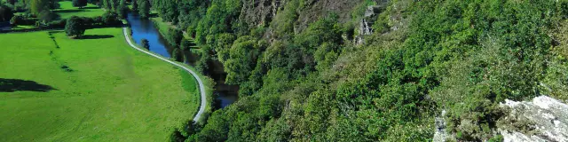 Luftaufnahme eines grünen Tals mit einem gewundenen Fluss und bewaldeten Hügeln