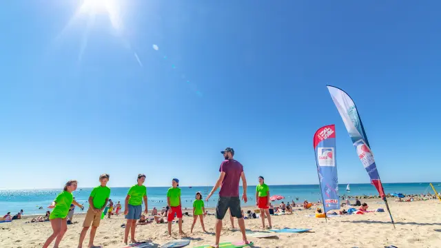 Eine Gruppe von Menschen, die Surfunterricht an einem sonnigen Strand nehmen