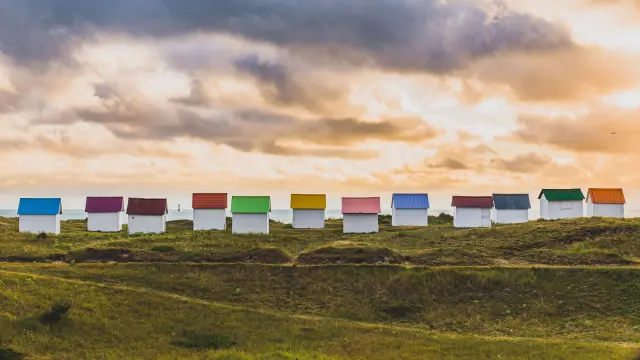 Voiliers amarrés dans un port avec des bâtiments colorés en arrière-plan au coucher du soleil