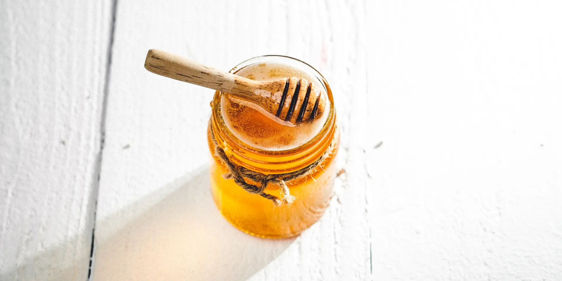 Un pot de miel transparent avec une cuillère en bois à l'intérieur