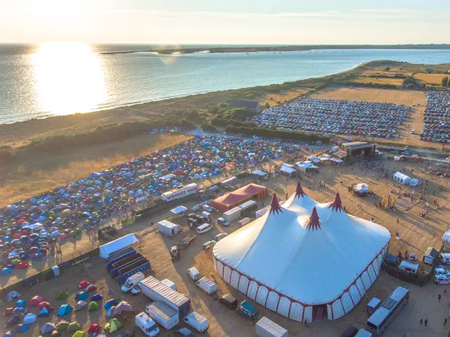 Yachthafen mit vertäuten Segelbooten und beleuchteten Terrassen in der Abenddämmerung