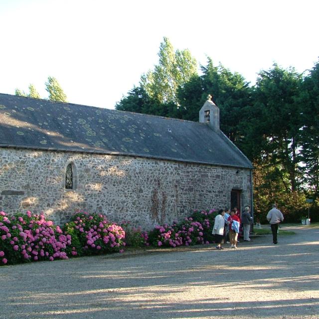 Steinkapelle mit rosa blühenden Sträuchern draußen
