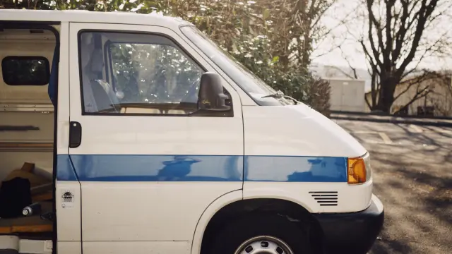 Ein weißer Lieferwagen im sonnigen Wald geparkt