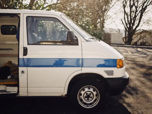 Un van blanc garé dans une forêt ensoleillée