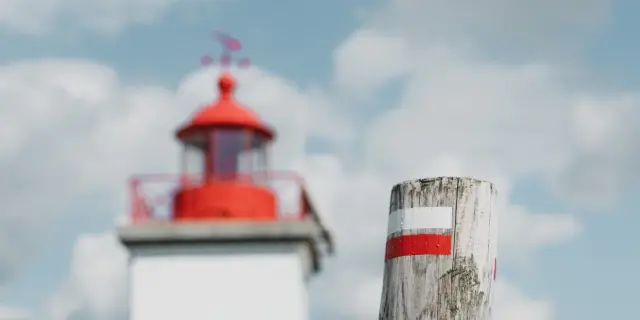 Phare côtier peint en bandes rouges et blanches avec une antenne à proximité