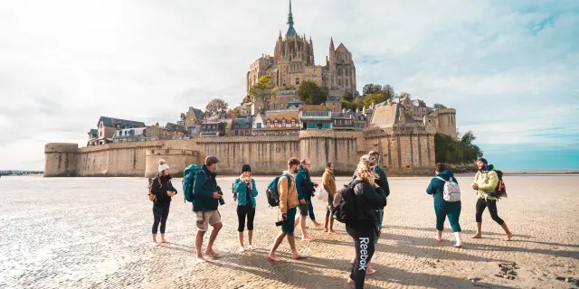 Groupe de randonneurs marchant sur la plage vers le Mont Saint-Michel
