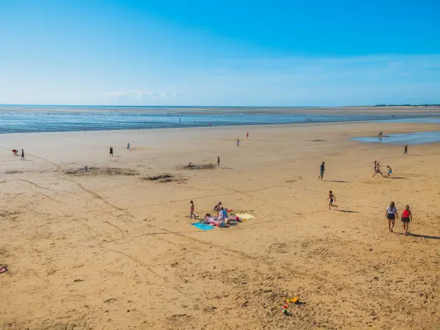 Menschen spazieren auf einem Sandstrand mit dem Ozean im Hintergrund