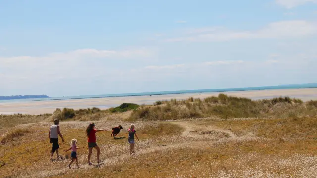 Four children running and playing on a sandy beach with waves in the background
