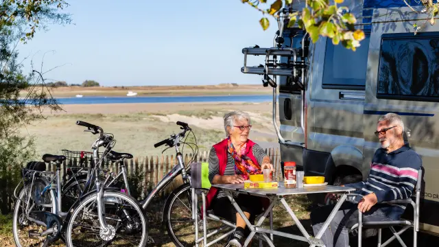 Deux personnes pique-niquent près d'un plan d'eau avec des vélos à proximité