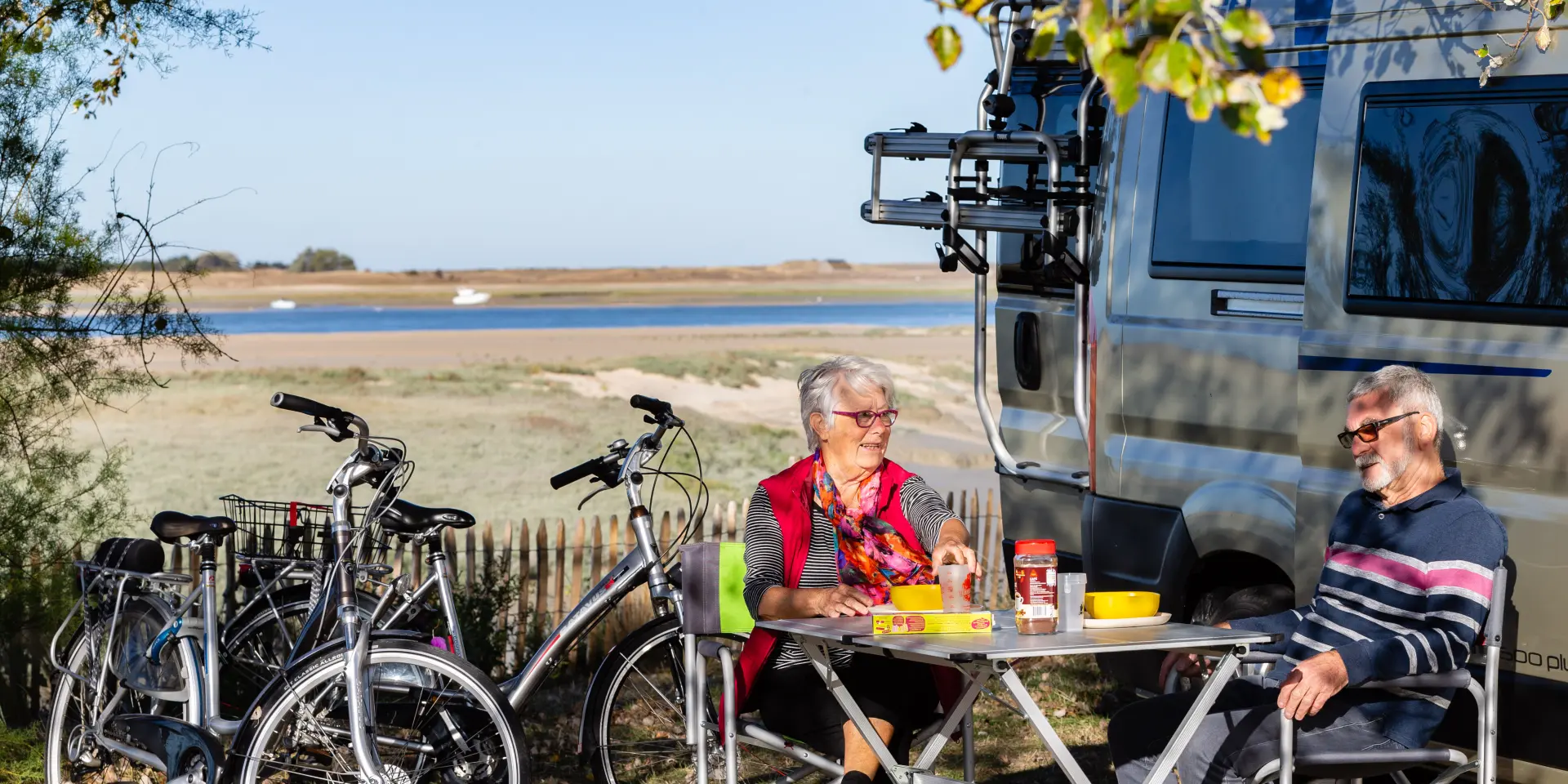 Deux personnes pique-niquent près d'un plan d'eau avec des vélos à proximité