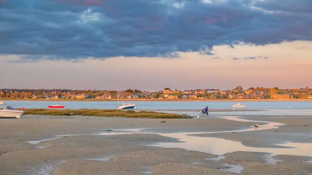 Strand mit Booten und Menschen beim Sonnenuntergang