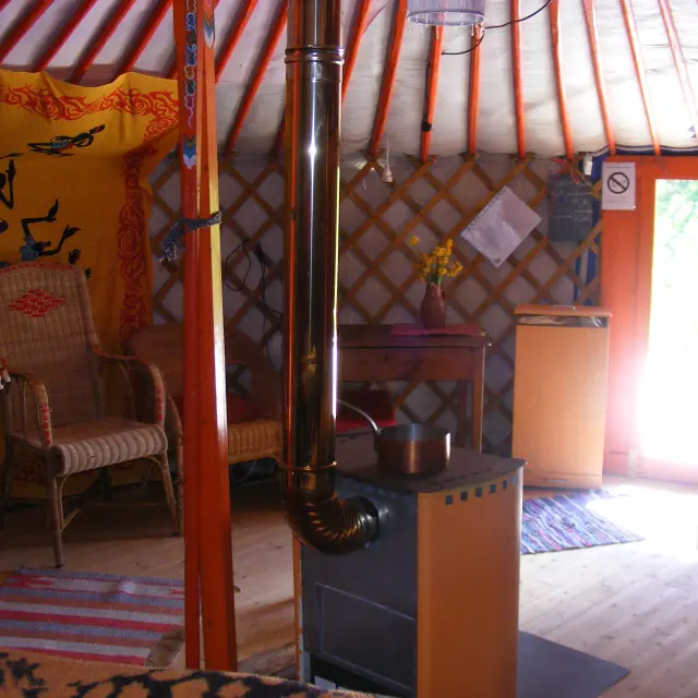 Intérieur d'une yourte avec un poêle, des chaises et des décorations murales