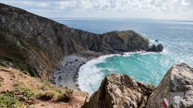 Coastal landscape with a rocky cove and clear turquoise water surrounded by cliffs