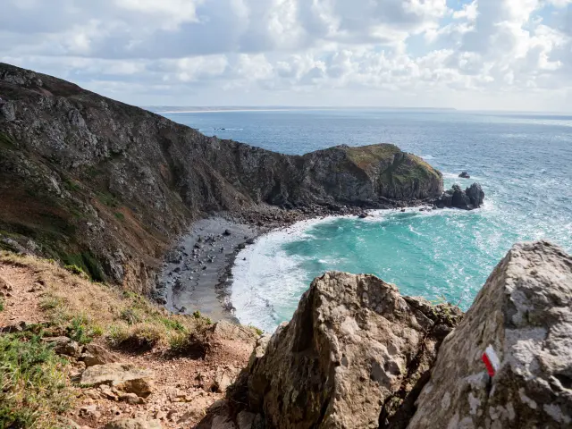 Küstenlandschaft mit einer felsigen Bucht und klarem türkisfarbenem Wasser, umgeben von Klippen