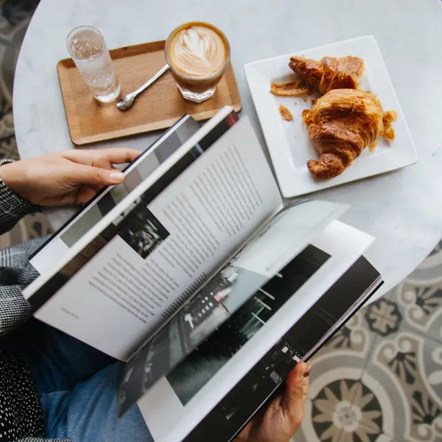 Une personne utilisant une fourchette pour goûter des pâtisseries posées sur une assiette en métal