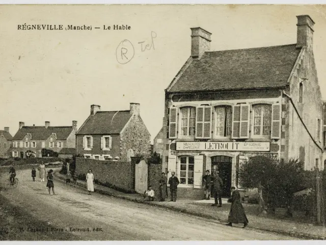 Rue avec des maisons en pierre et un bâtiment avec une enseigne à Regnéville sur Mer