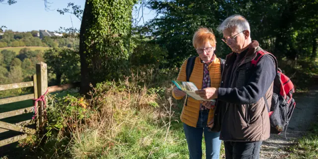 Two people hiking are consulting a map near a country path