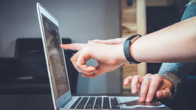 Deux personnes pointent l'écran d'un ordinateur portable