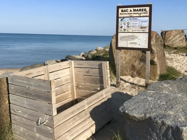 Un bac à marée en bois près de la plage avec un panneau d'information