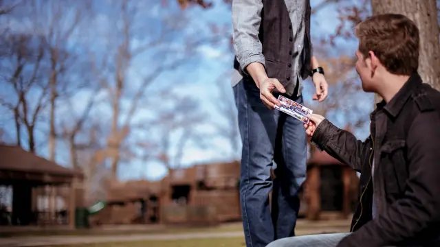 Deux personnes échangent un objet en extérieur