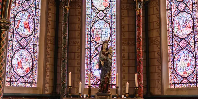 Autel avec des bougies et une statue devant des vitraux dans la cathédrale de Coutances
