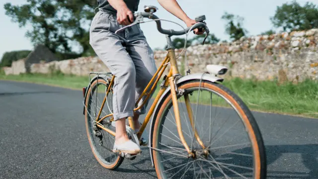Personne pédalant sur un vélo vintage sur une route de campagne