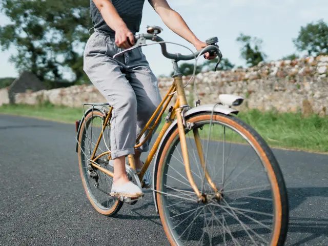 Personne pédalant sur un vélo vintage sur une route de campagne