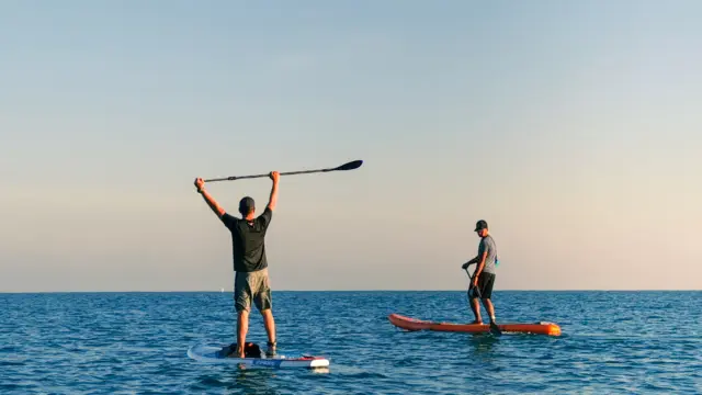 Deux personnes faisant du paddleboard sur une mer calme