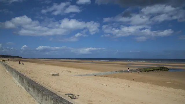 Plage de sable fin avec des voiliers amarrés et des personnes en arrière-plan