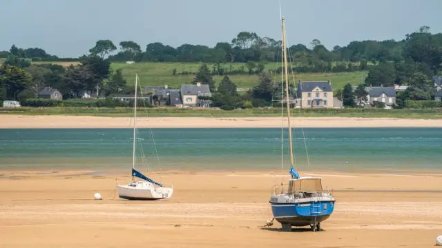 Zwei Boote auf einem Sandstrand gestrandet mit Häusern im Hintergrund