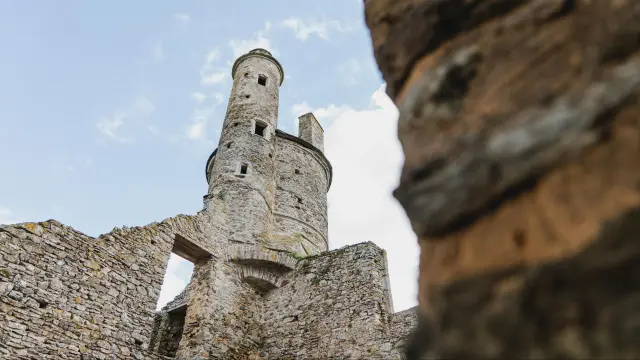 Tour en pierre de style médiéval avec créneaux et merlons, vue de bas en haut