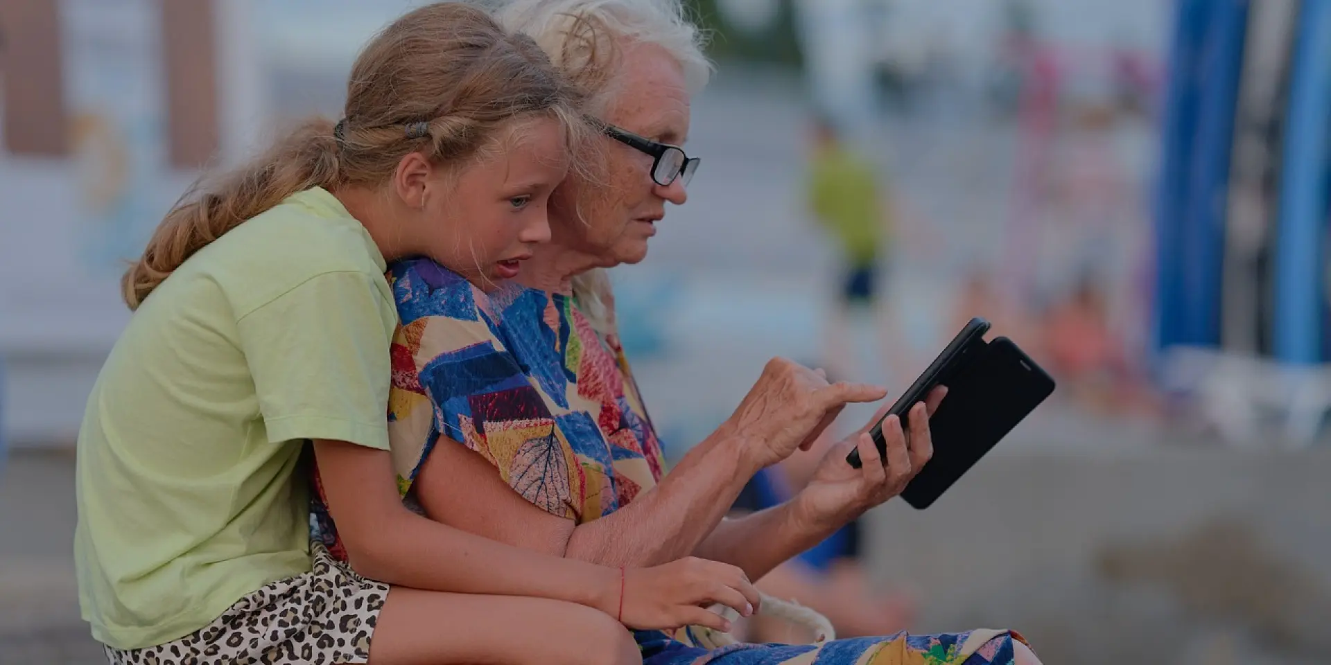 Une jeune fille et une personne âgée regardent un smartphone ensemble