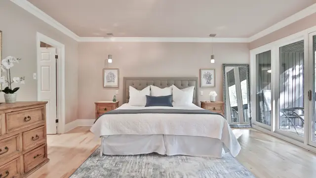 Chambre avec lit double, deux tables de chevet, un grand miroir et une porte-fenêtre