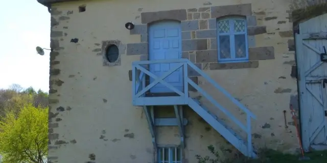 Tour en pierre grise avec escalier métallique extérieur et fenêtres à meneaux