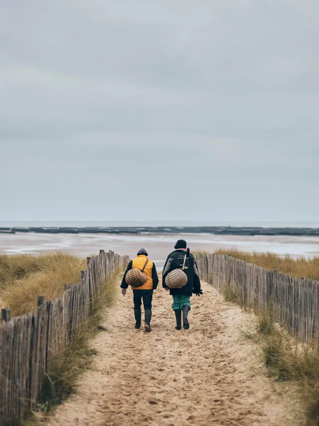 Deux personnes marchant sur un chemin de sable vers la mer à Annoville