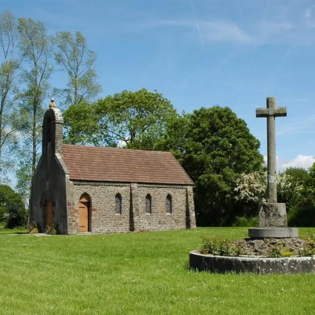 Église en pierre avec un toit rouge, entourée d'arbres et d'un cimetière
