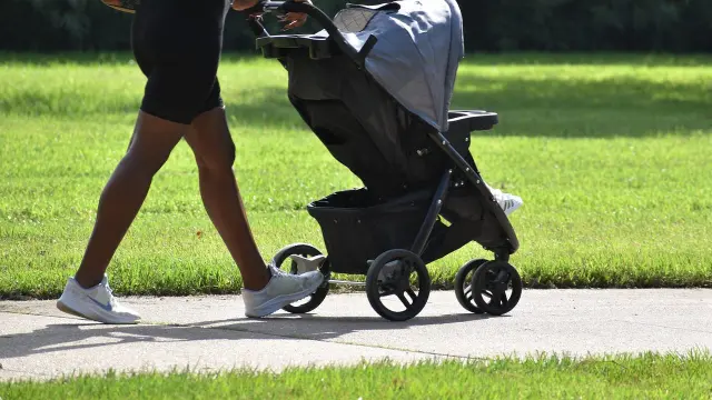 Une personne pousse une poussette sur un chemin de terre
