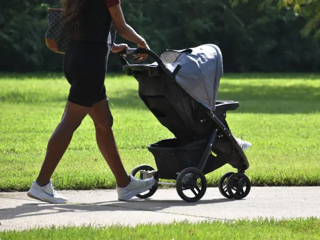 Une personne pousse une poussette sur un chemin de terre