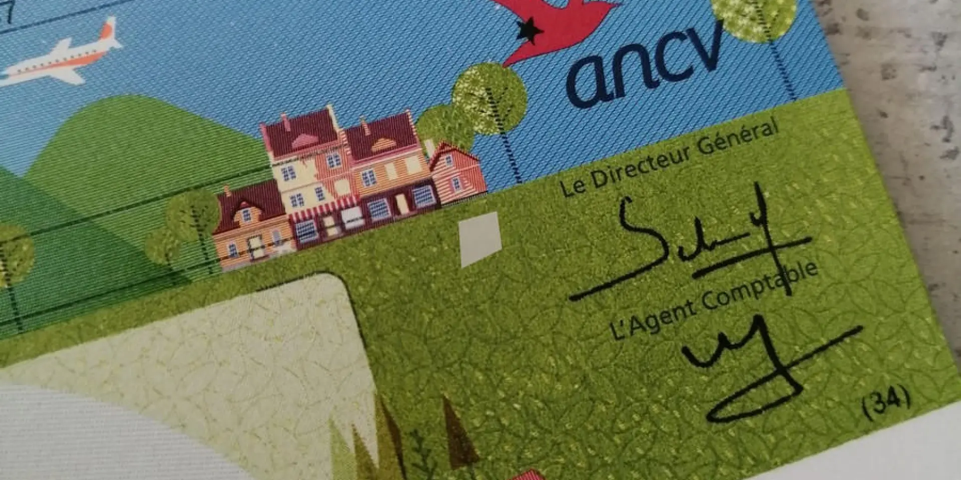 Un chèque de 10€ émis par ANCV avec des illustrations de paysages et de bâtiments