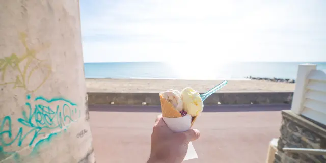 Une main tenant un cône de glace à deux boules à Agon Coutainville devant la mer