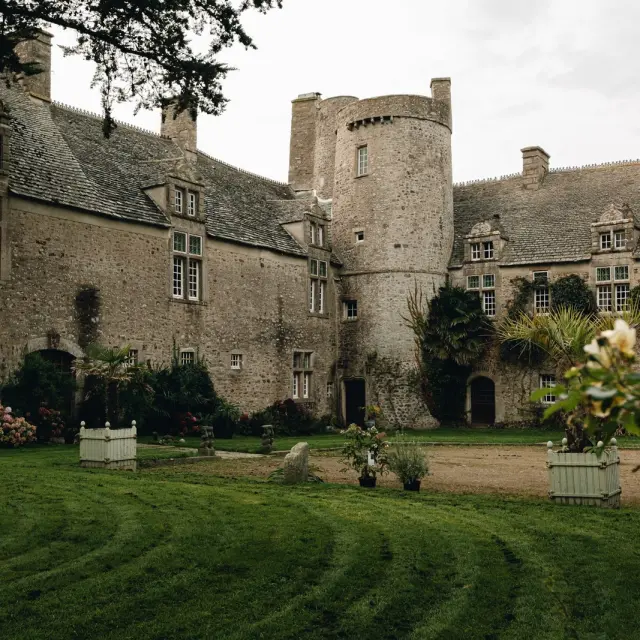 Medieval stone castle with crenellated towers, surrounded by a lush park