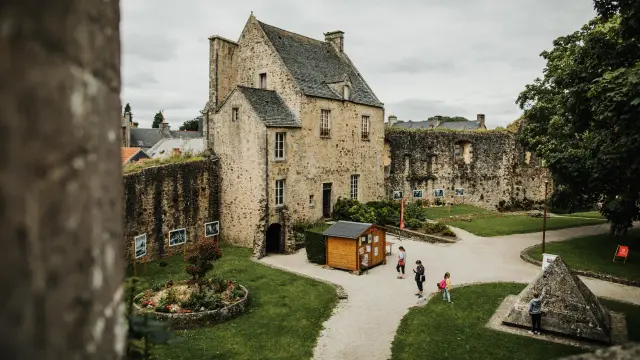 Stone castle with crenellated towers, surrounded by a river and gardens