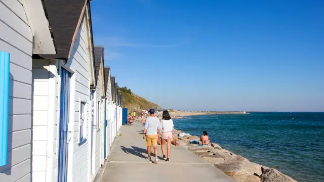 Seafront promenade with people walking and moored sailboats