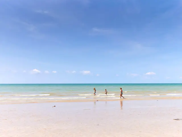 Drei Kinder laufen auf einem feinen Sandstrand