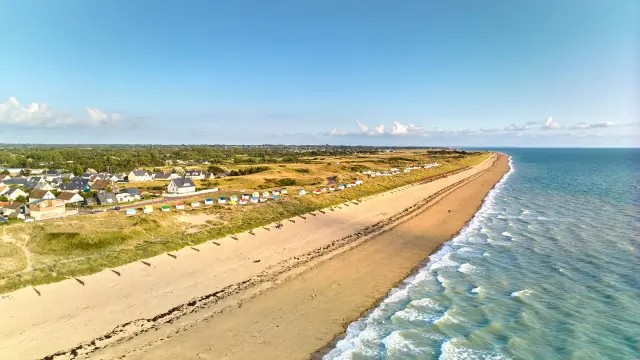 Ein langer Sandstrand mit Häusern und bunten Strandkabinen