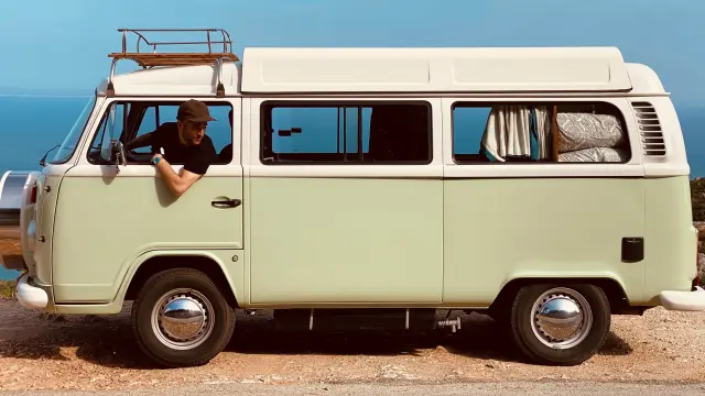 Camion utilitaire jaune des années 1950 avec une cabine en bois, garé sur un sol en terre